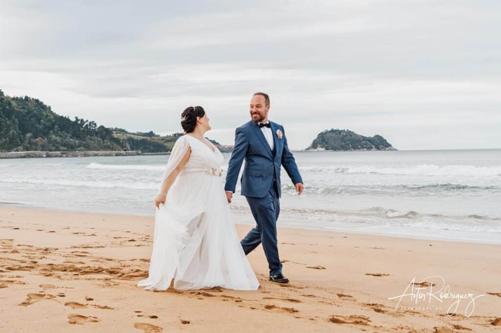 El novio y la novia pasean por la arena frente al mar Cantábrico en Zarautz, cerca del restaurante de Karlos Arguiñano.