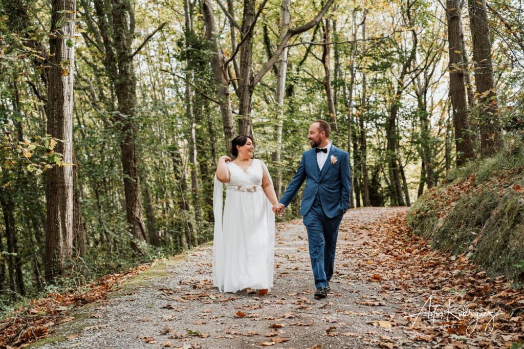 Pareja de novios caminando de la mano por un sendero otoñal en el Parque Natural de Pagoeta, Aia. Boda en Gipuzkoa.